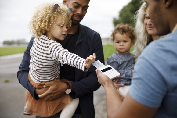 A child pushes a credit card into an electronic payment portal.
