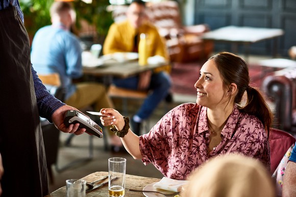 A person sitting in a restaurant and paying with a credit card.