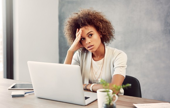 A person looking stressed and dejected while sitting at the computer.