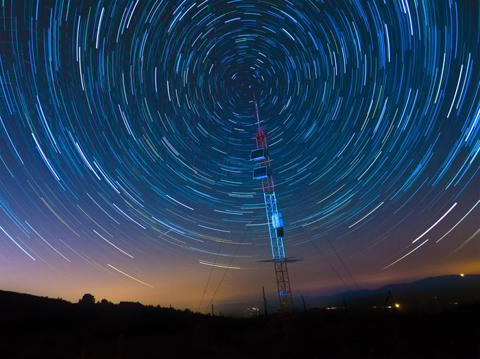 A satellite communications array under a starry sky.
