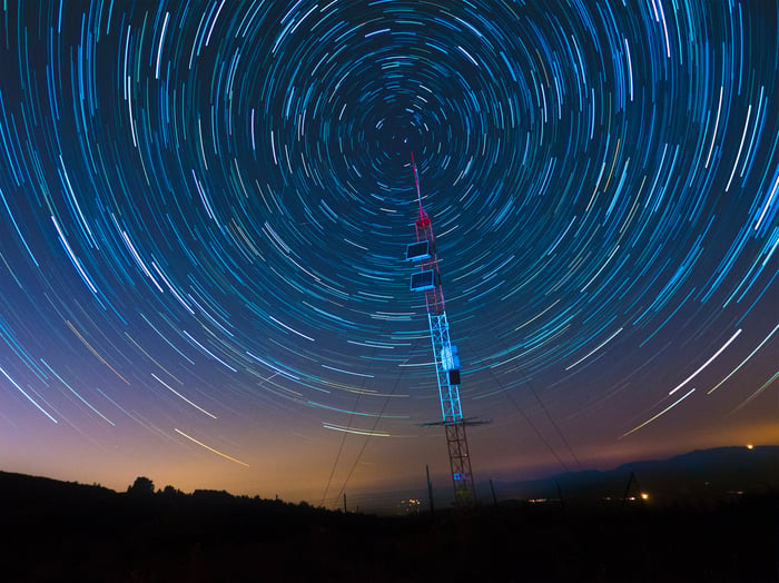 A satellite communications array under a starry sky.