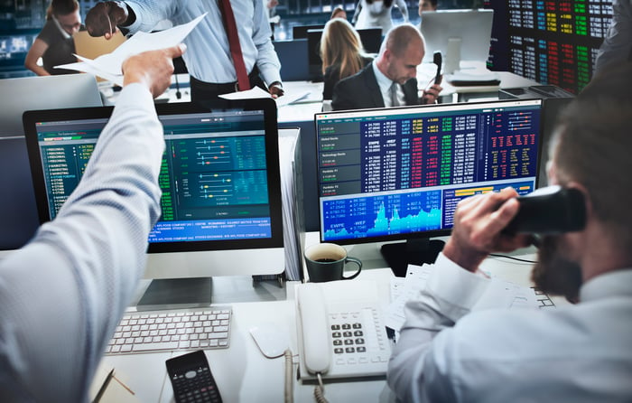 Professional stock traders at work, with financial data displayed on their computer screens.