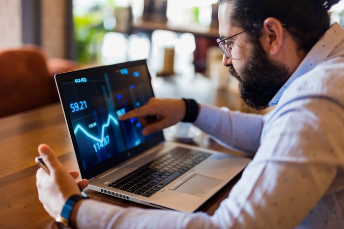 A man points to a stock chart on a laptop.