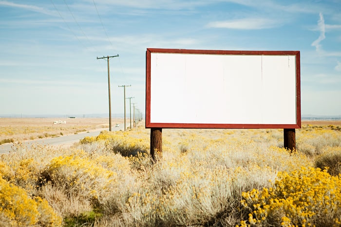 A blank  billboard on the side of a desert highway. 