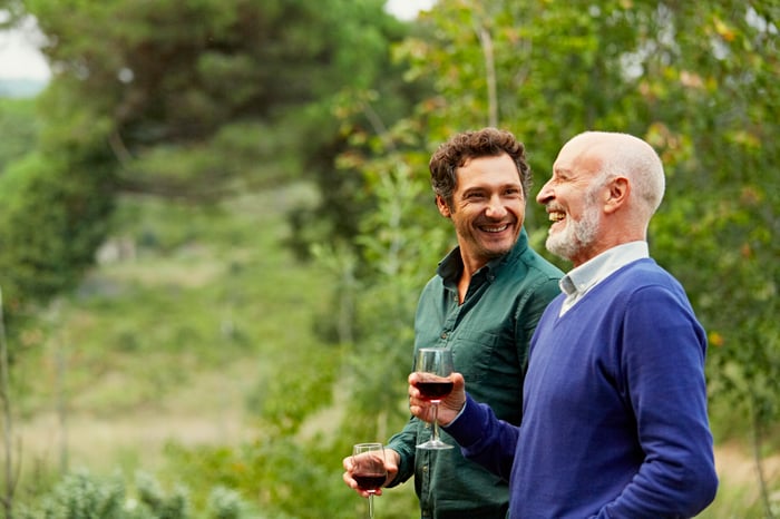 Two smiling people holding wine glasses outdoors.