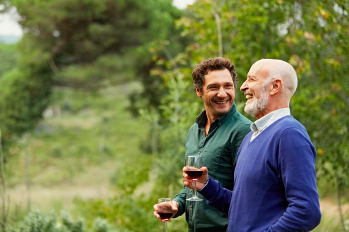 Two smiling people holding wine glasses outdoors.