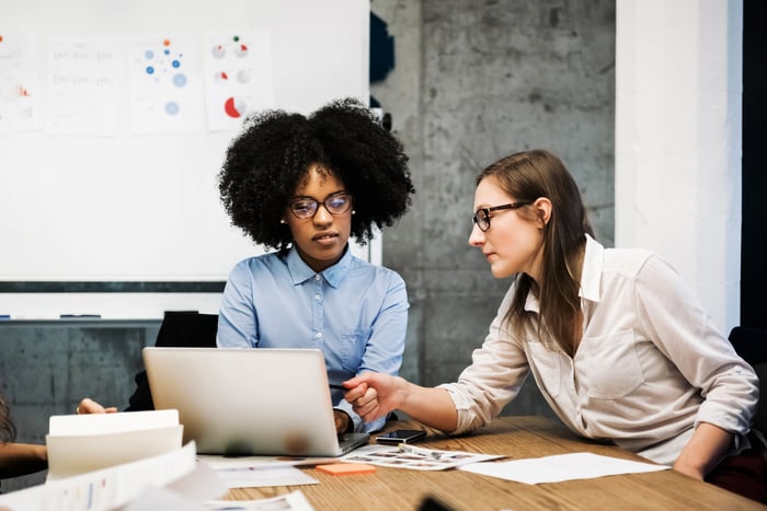 Two people using a laptop in a meeting room. 