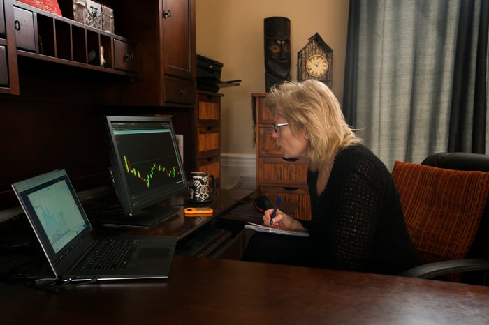 A woman looks at a falling stock chart on a computer.