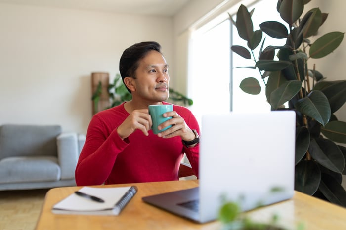 Person at laptop holding mug