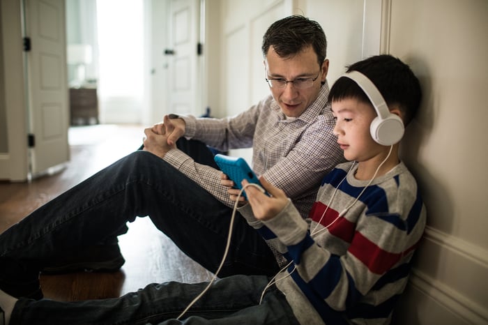 A child sits on the floor watching a tablet.