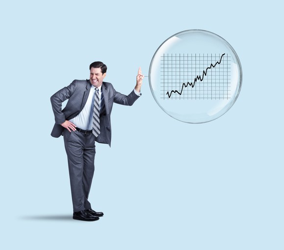 Man in suit poking a stock market bubble with a pin.