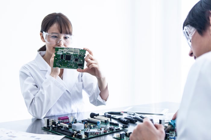 Two people in laboratory coats examining semiconductors