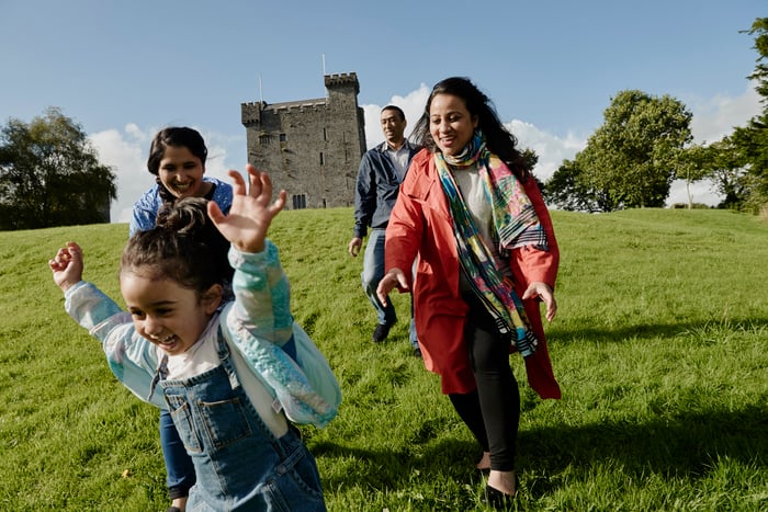 A family on the grass in front of a castle rented through Airbnb.