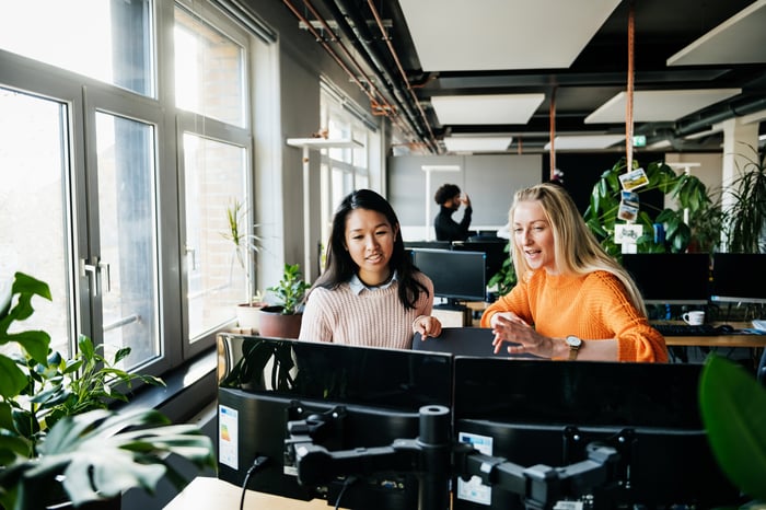 Two women sitting in front of computers in an office.