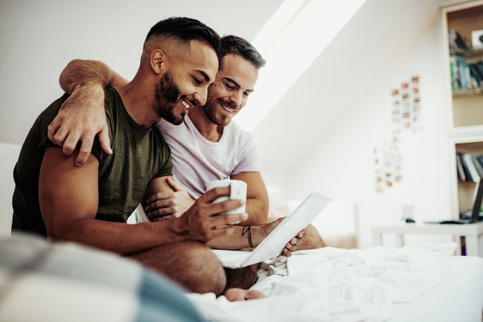 A couple sitting in bed looking at a computer.