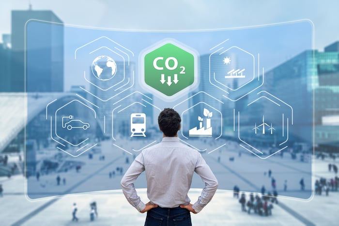 A person looking at a city street, with icons representing falling carbon dioxide emissions overlaid on top.