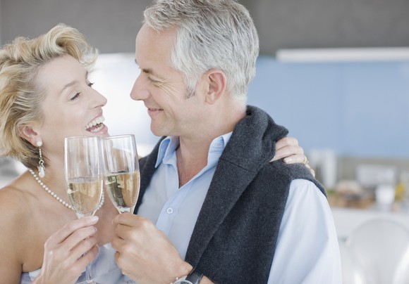 an elderly couple clinking champagne glasses