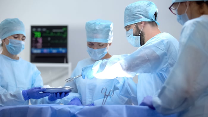 A healthcare team led by a surgeon performs a procedure on a patient.