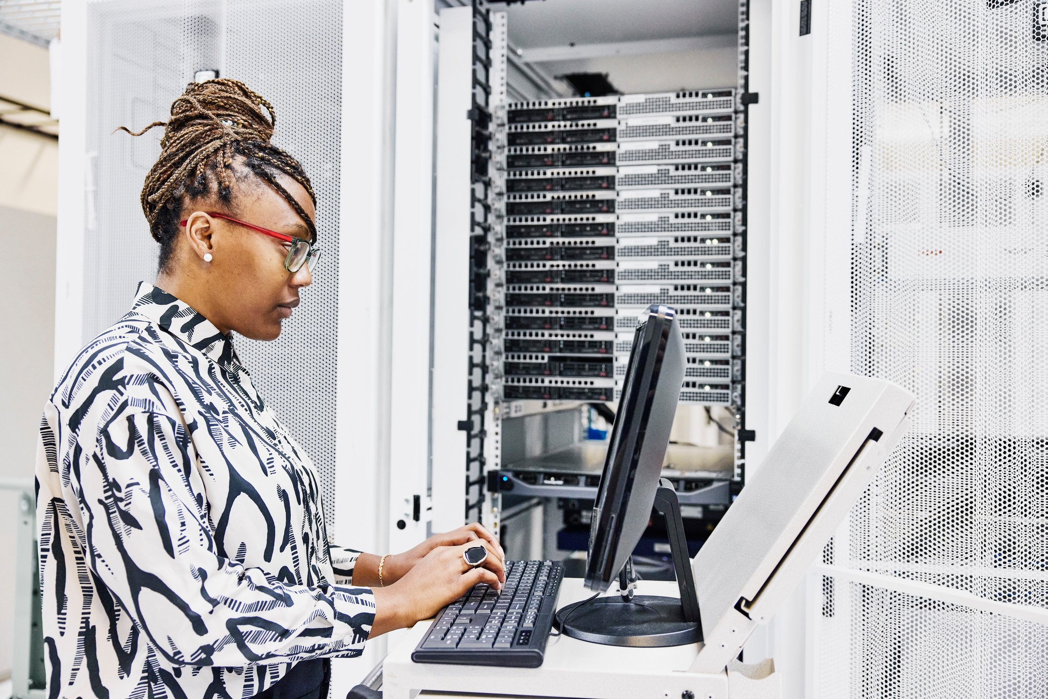 Information technology professional working in a server room with a laptop