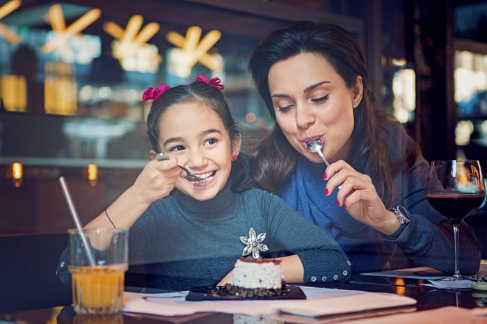 A parent and child sharing food in a restaurant.