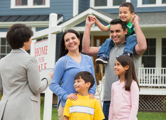 A family outside their new home talking to their realtor.