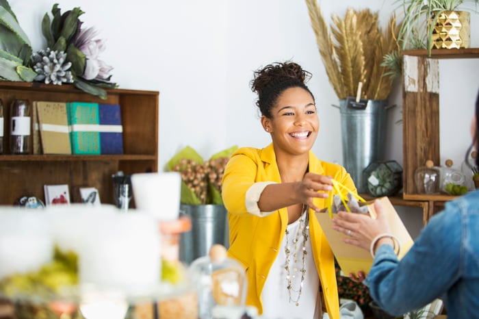 Small business owner handing a purchase to a customer