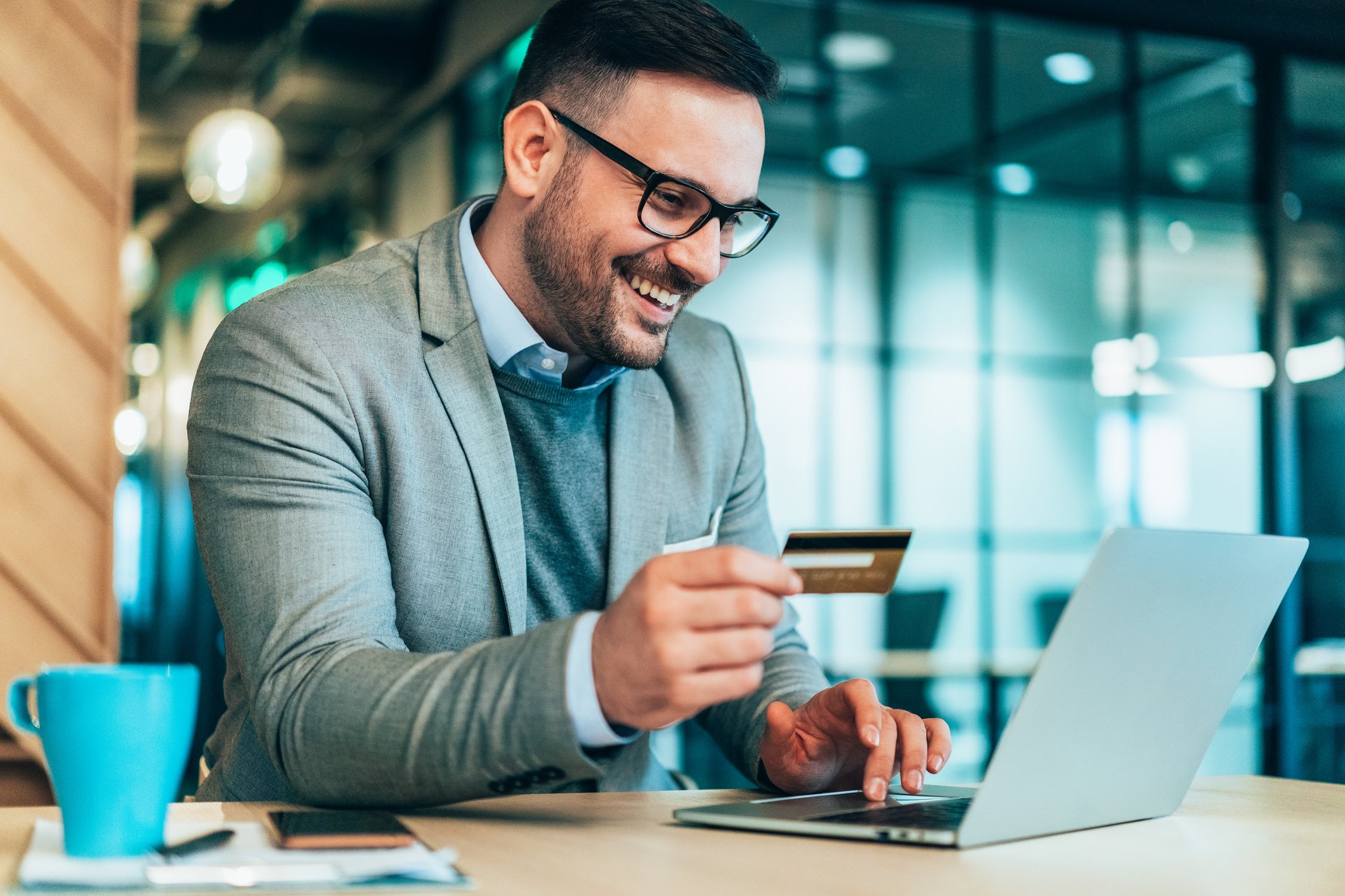 A person using a laptop computer holding a credit card