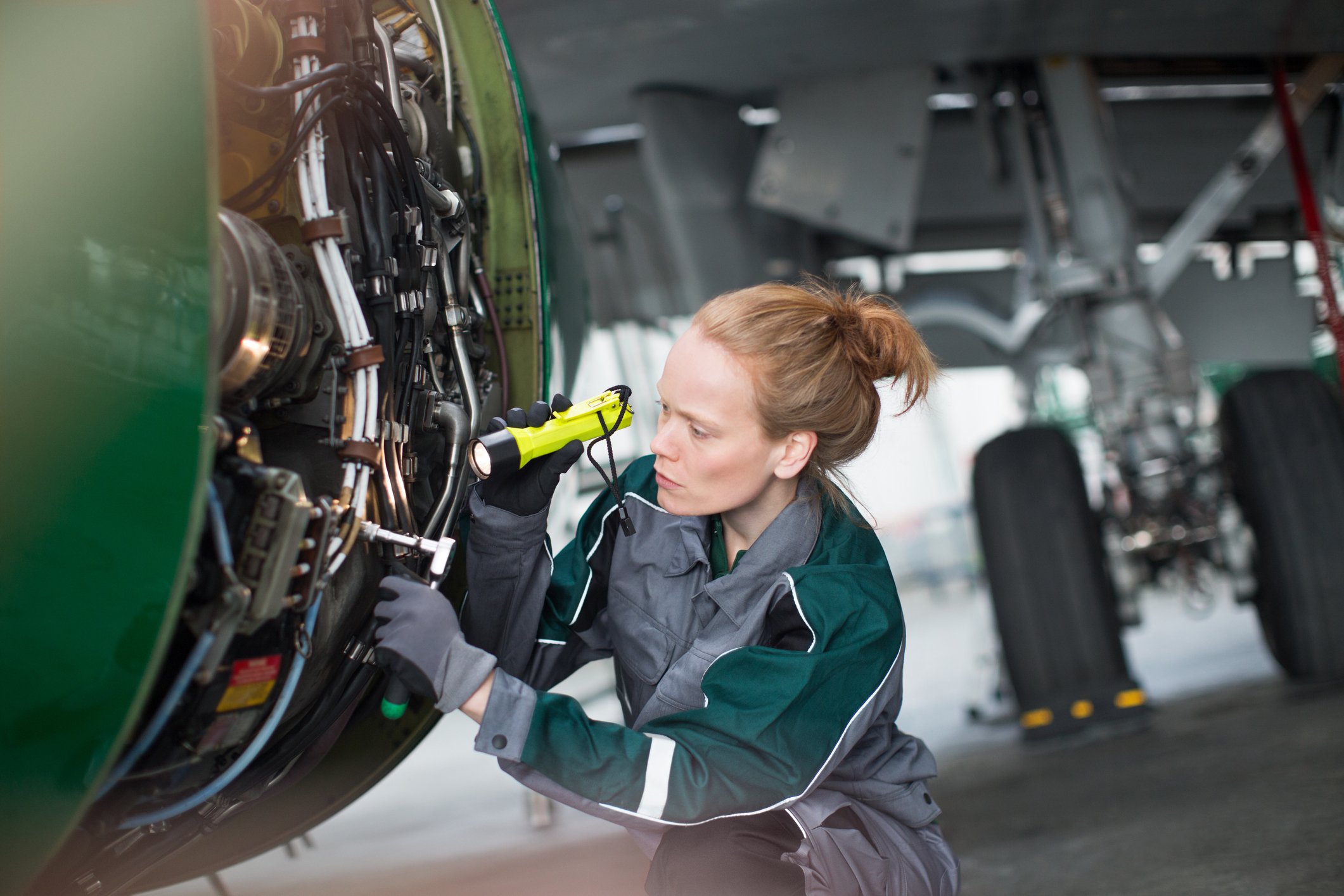 Engineer using flashlight to analyze airplane part source getty