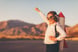 A girl with a toy rocket attached to her back raises her arm.