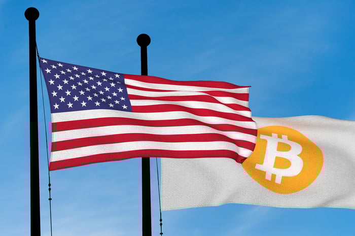 US flag flying next to a flag emblazoned with the Bitcoin symbol