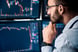 A person analyzing falling stock price charts on computer screens.
