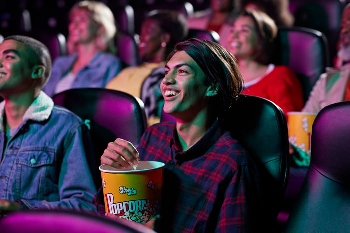 A moviegoer eating popcorn in a crowded theater. 