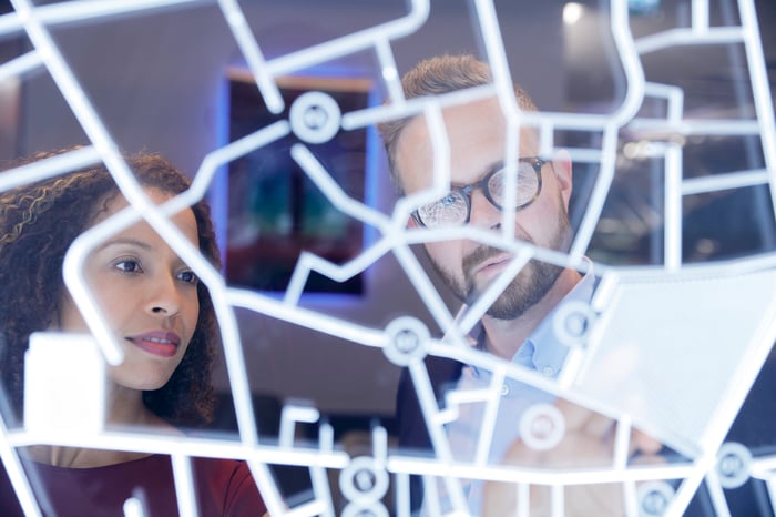 Two people looking at a board with a bunch of lines on it.