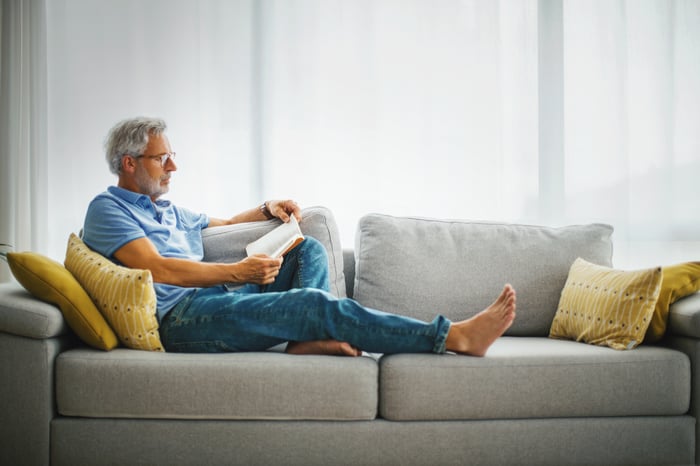 Person reading book on couch