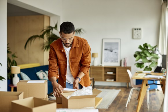 A person looking at boxes in a living room.