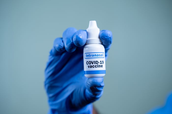 Gloved hand holding a COVID-19 intranasal vaccine container.