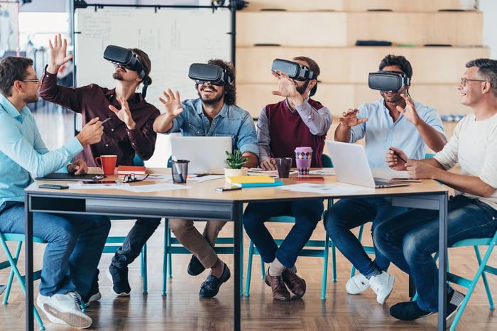 Workgroup using virtual 3D headsets in office setting and smiling