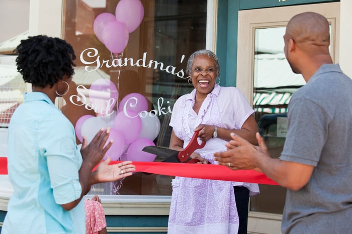 A small business owner cutting the ribbon at their grand opening