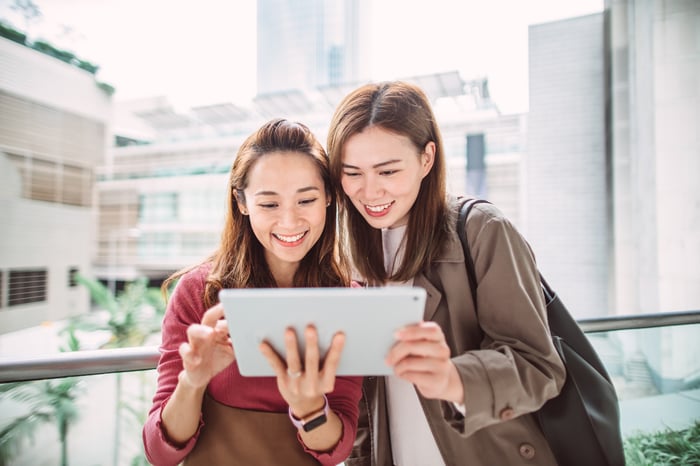 Two women holding and looking at a tablet computer.