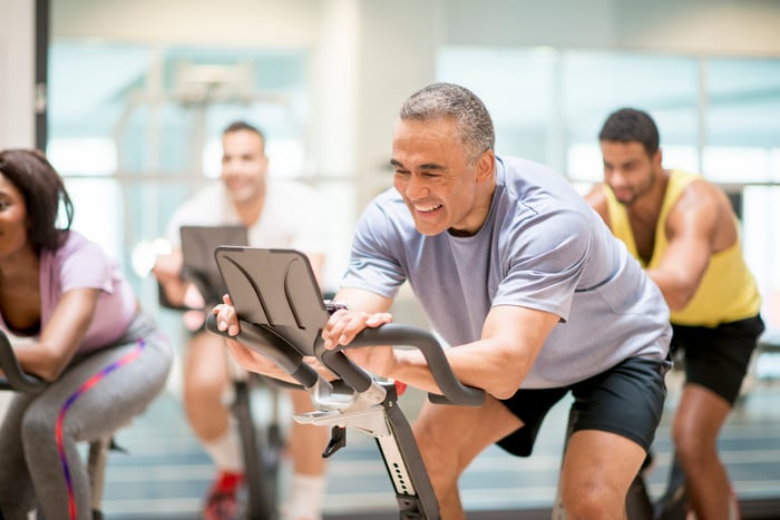 A man on a connected fitness bike with a group of people on bikes.