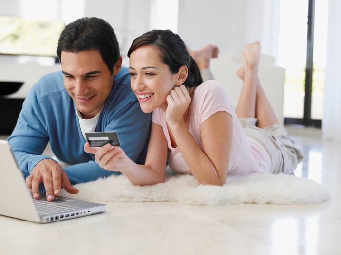 Two people with credit card and laptop.