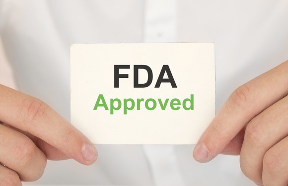 Two hands holding a card with "FDA approved" printed on it.