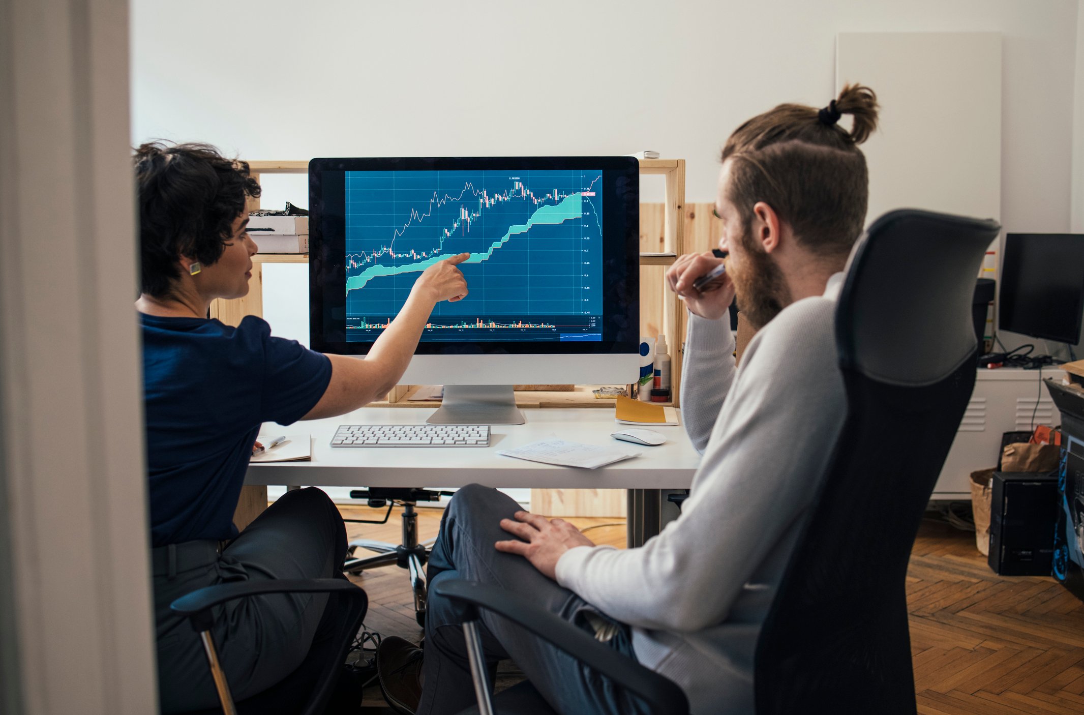 an investor points out financial data on computer to another