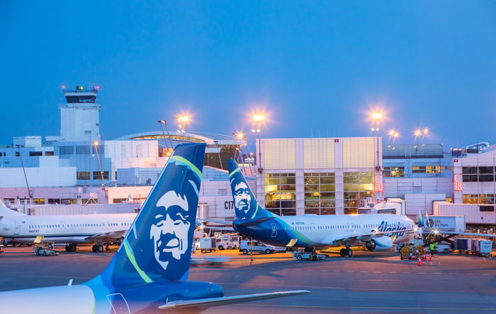 Alaska Airlines planes at their gates in the evening.