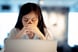 A concerned woman with closed eyes in front of a laptop.