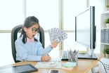 Child at desk with lots of cash -- GettyImages-847213554