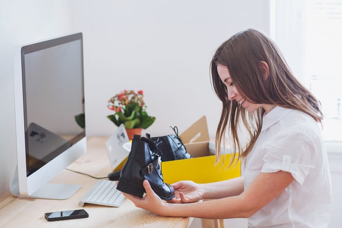 A smiling person opening their online shopping order at home.