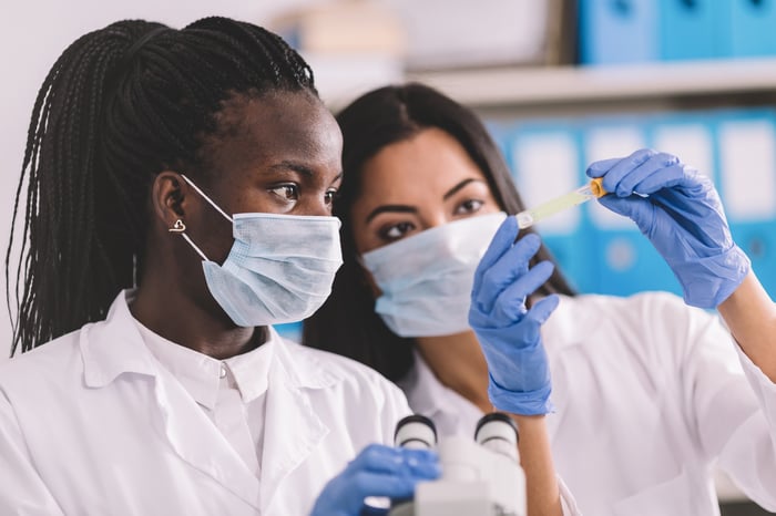 Doctors collaborate on research while looking at a test tube.