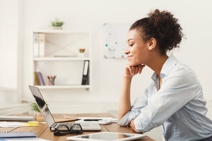 A person sitting at their home office desk using a laptop computer