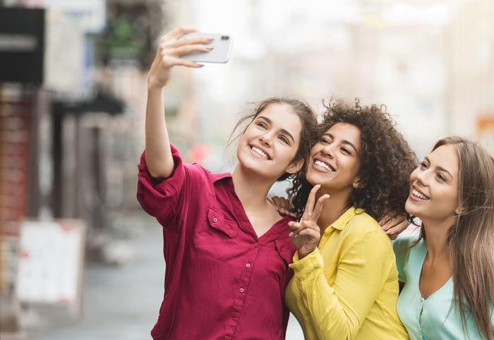 Three friends taking a smiling selfie with a smart phone